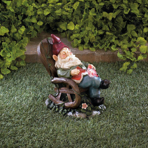 Gnome with red hat sitting in rocking chair with bird and book