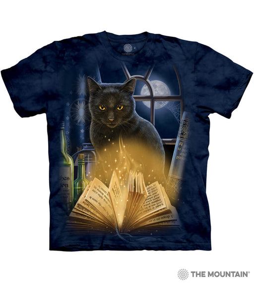 Mottled blue tee shirt with black cat sitting in front of window looking at glowing, sparkling magic book. Full moon outside, bottles and another book on the windowsill
