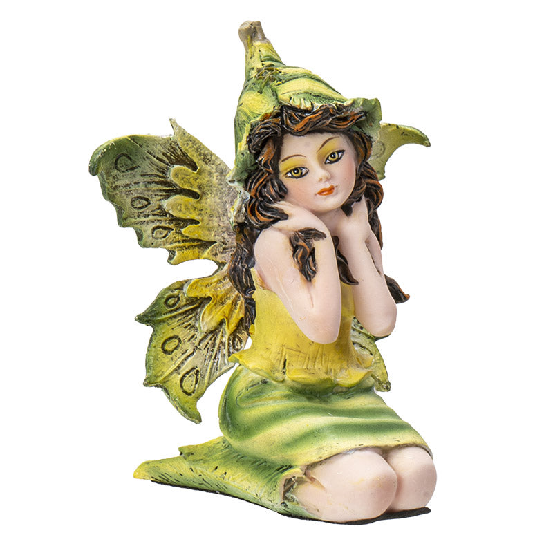 Figurine of sitting fairy in green and yellow dress with matching wings and hat, brown hair, yellow-brown eyes