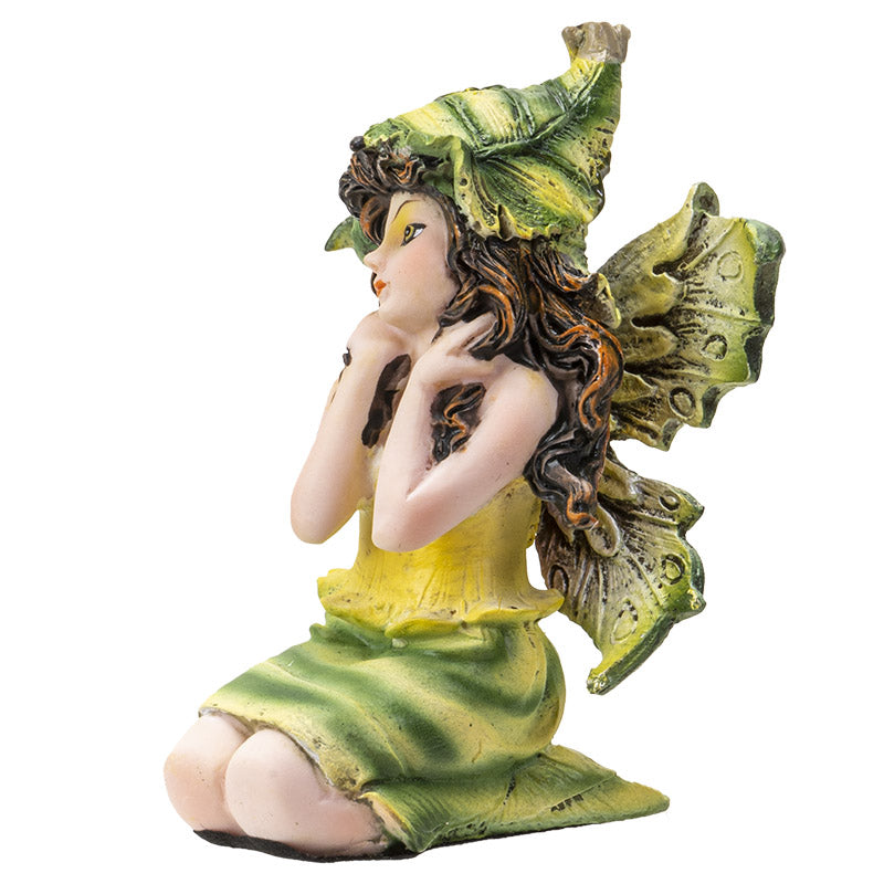 Figurine of sitting fairy in green and yellow dress with matching wings and hat, brown hair, yellow-brown eyes