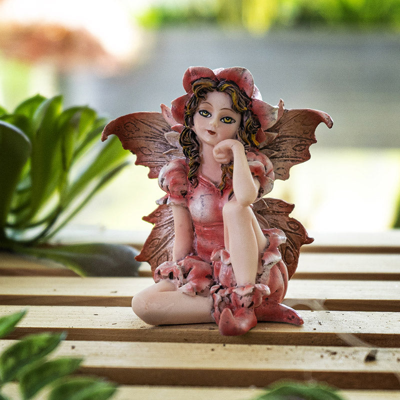 Fairy figurine, pink dress, wings and flower hat. Blond-streaked brown hair with golden yellow-brown eyes