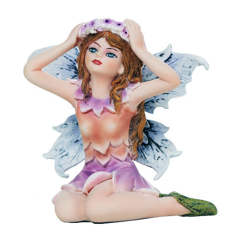 Fairy figurine with wings and floral crown on a white background. Wearing a peach and purple flower dress with blue wings, brown hair, green shoes