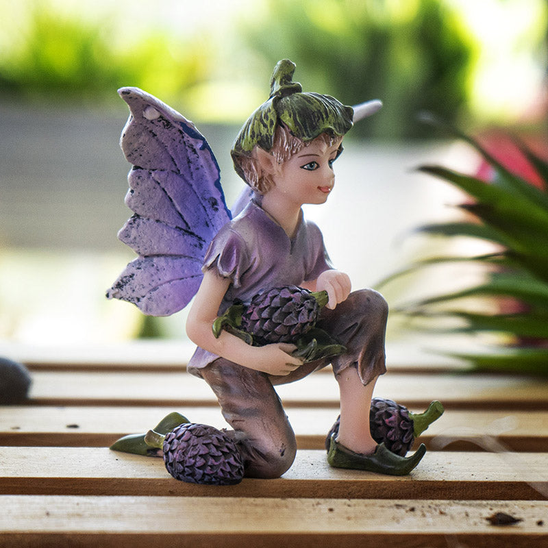 Fairy boy figurine with purple wings, green flower bud hat, holding a berry with more berries next to him