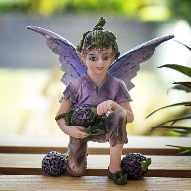 Fairy boy figurine with purple wings, green flower bud hat, holding a berry with more berries next to him