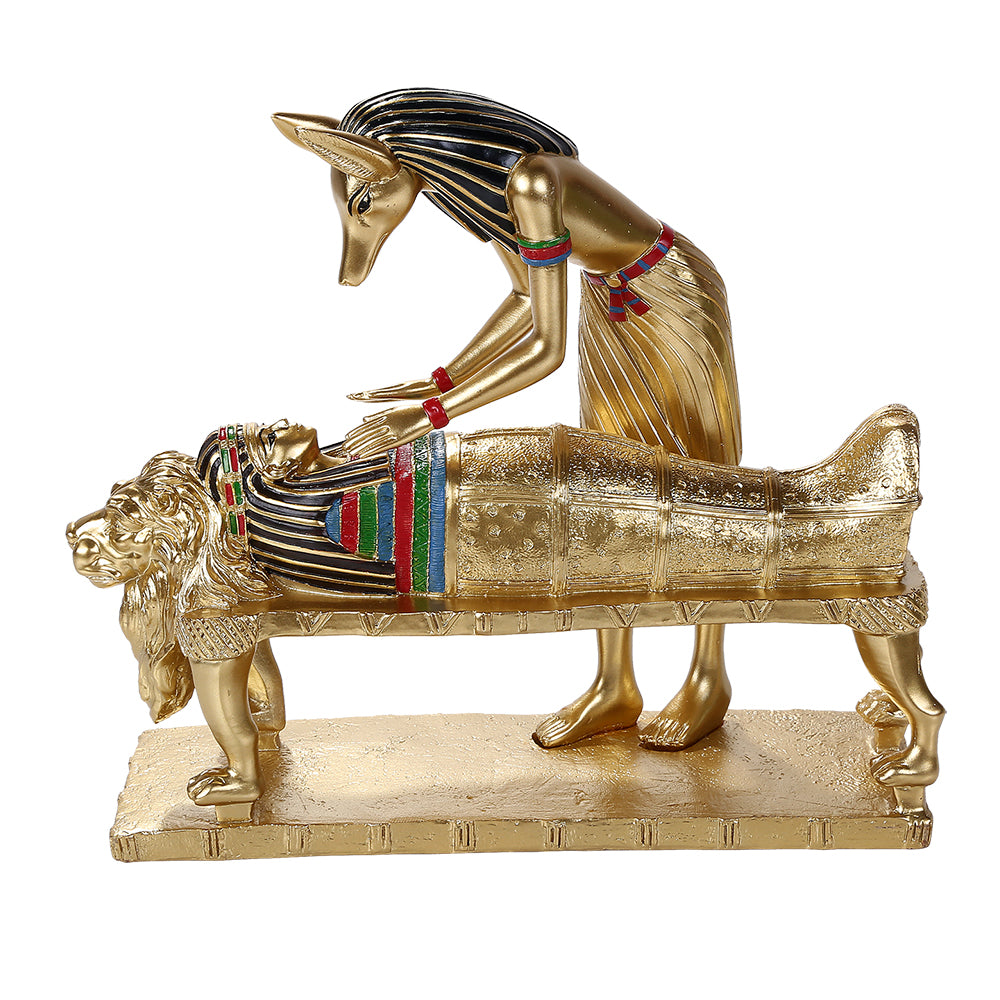 Figurine in faux gold of Anubis the jackal headed Egyptian god hovering over a mummy sarcophagus