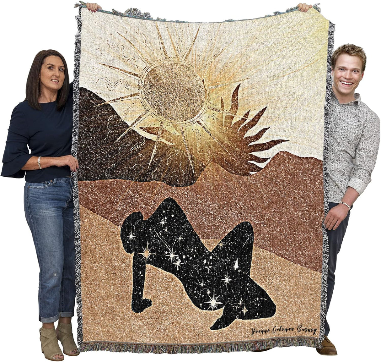 Two people holding a large blanket with a sun and silhouette design.