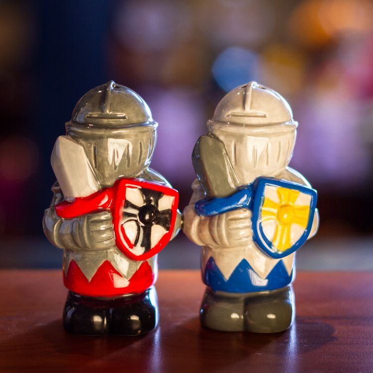 Salt and pepper shakers shaped like knights, one dark gray with red and one light gray with blue, holding swords