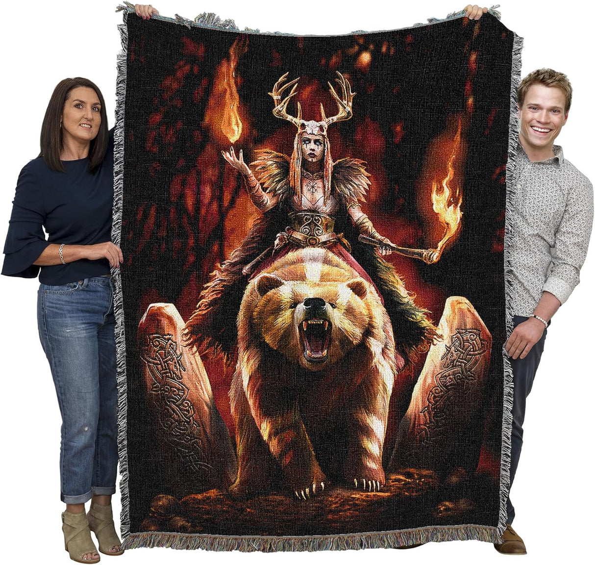 Woven blanket with a fantasy design of a warrior woman on a bear with flames and stone carvings, held by two people to show large size
