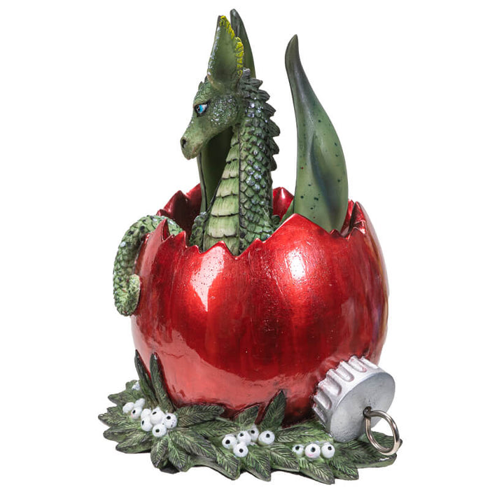 Figurine of a green dragon inside of a red broken Christmas ornament on berries and leaves