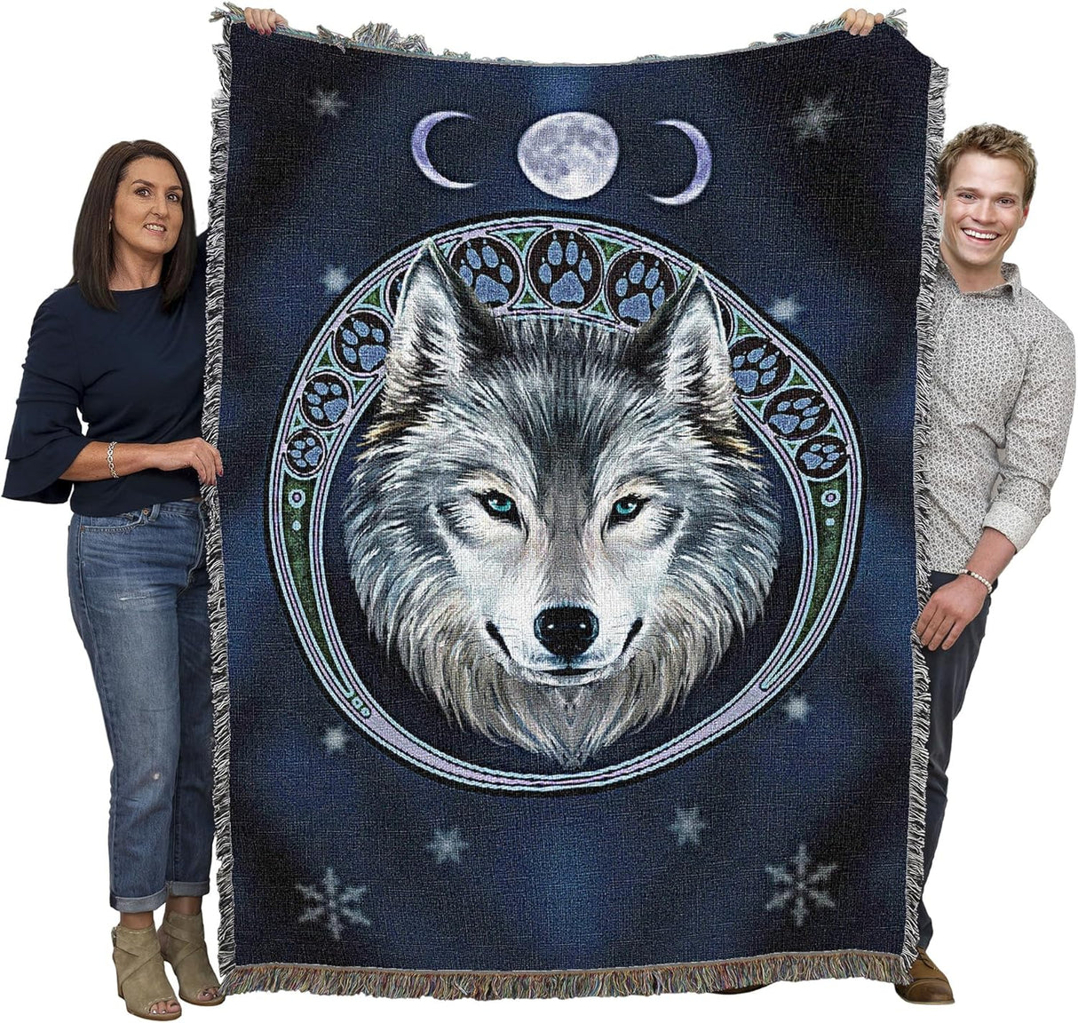Two people holding a blanket with a wolf design and moon phases.