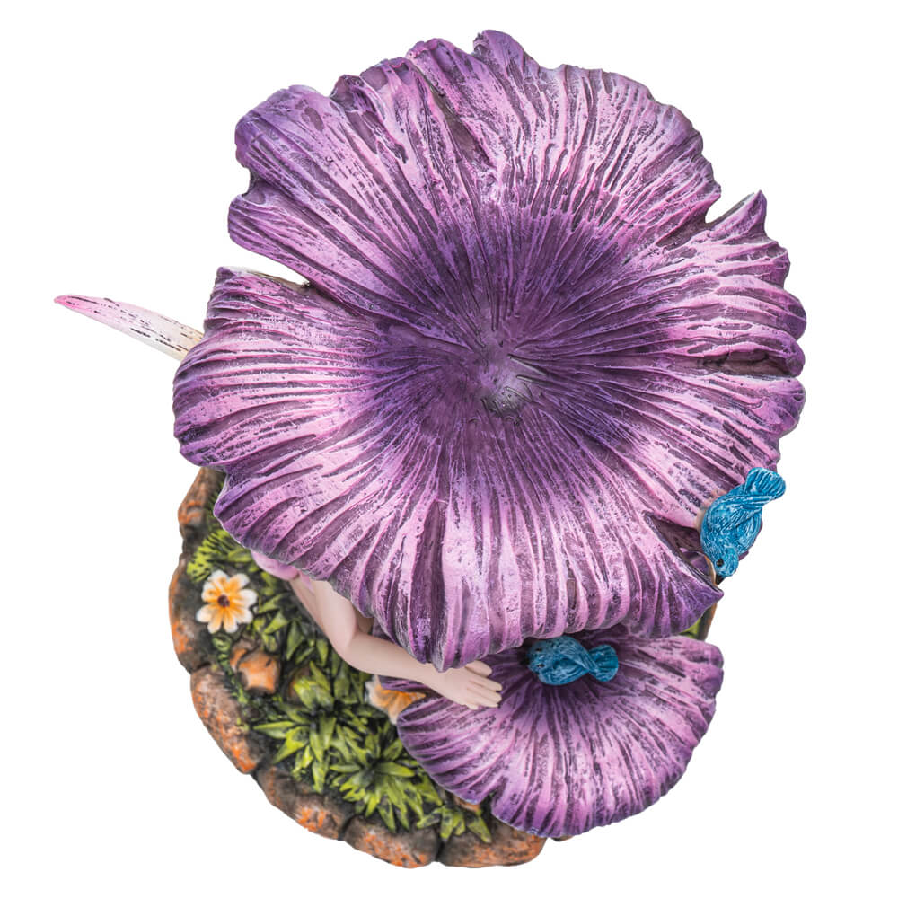 Blond pixie with pink and yellow wings sits under purple flowers with two blue birds. Shown from the top