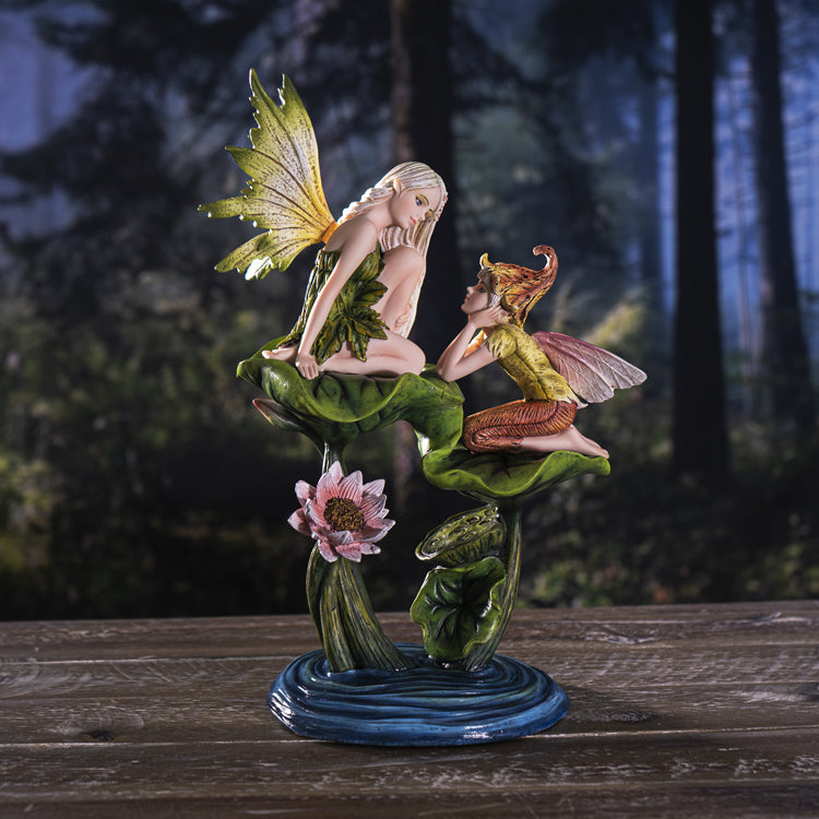 This figurine has a fairy sitting with an elf. The fairy sits on a higher leaf, looking down at the elf, and both of the leaves and a flower are above a pond of blue water that forms the base. The fairy has a green leaf dress with green and yellow wings, and pale white hair. The elf has a yellow shirt and orange-tan pants, a flower bud had, and pink wings.