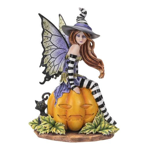 Figurine of a fairy in black and white stripes with purple and green accents sitting on a pumpkin next to a black cat