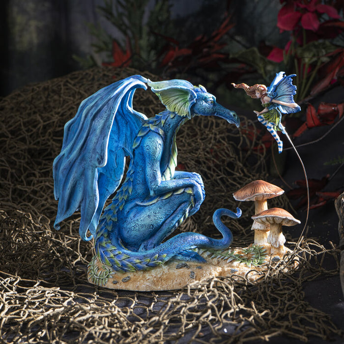 Figurine of a blue dragon and a fairy hovering with blue wings above mushrooms.