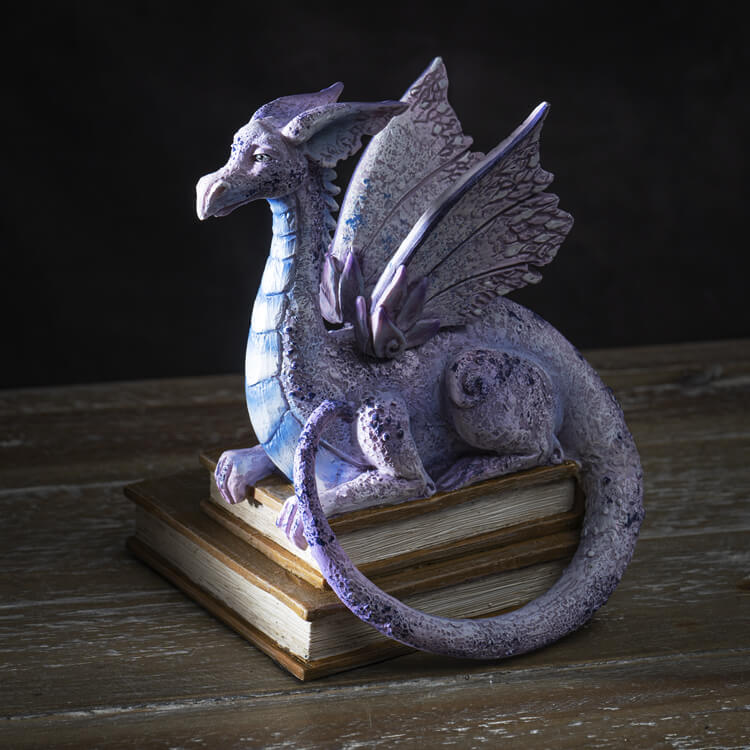 Figurine of a pale purple dragon perched on two books
