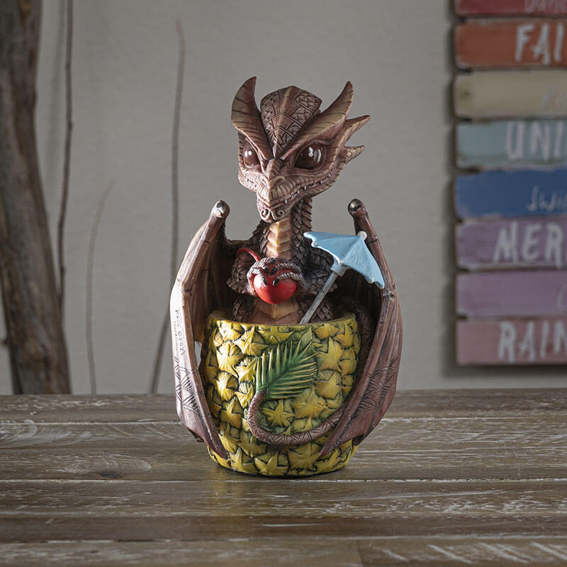 Mai Tai dragon with brown scales sitting in pineapple holding a cherry, with a blue drink umbrella