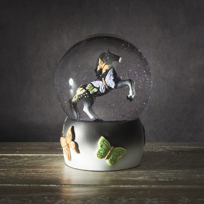 Snowglobe with black rearing horse and butterfly designs with purple glitter in the globe, and a base of black and white with more butterflies