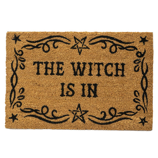 Natural tan doormat with black text reading "THE WITCH IS IN" surrounded by a star and swirl border