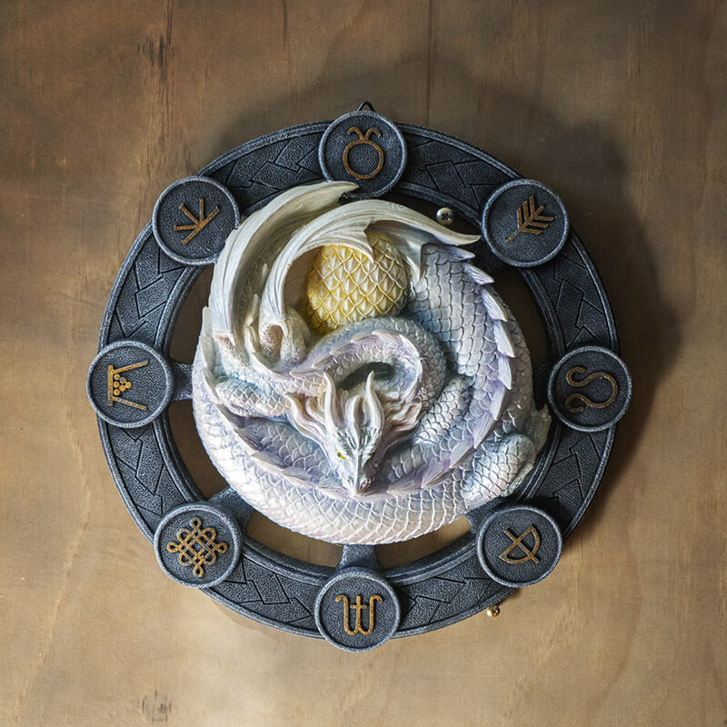 White Ostara dragon on a black wheel with gold symbols