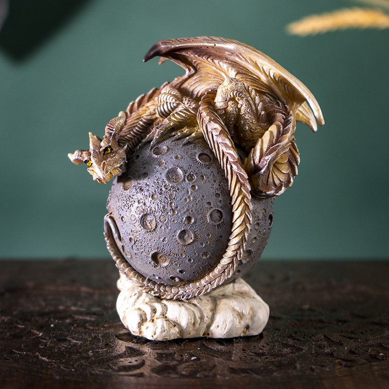 Figurine of a tan dragon on a gray moon orb