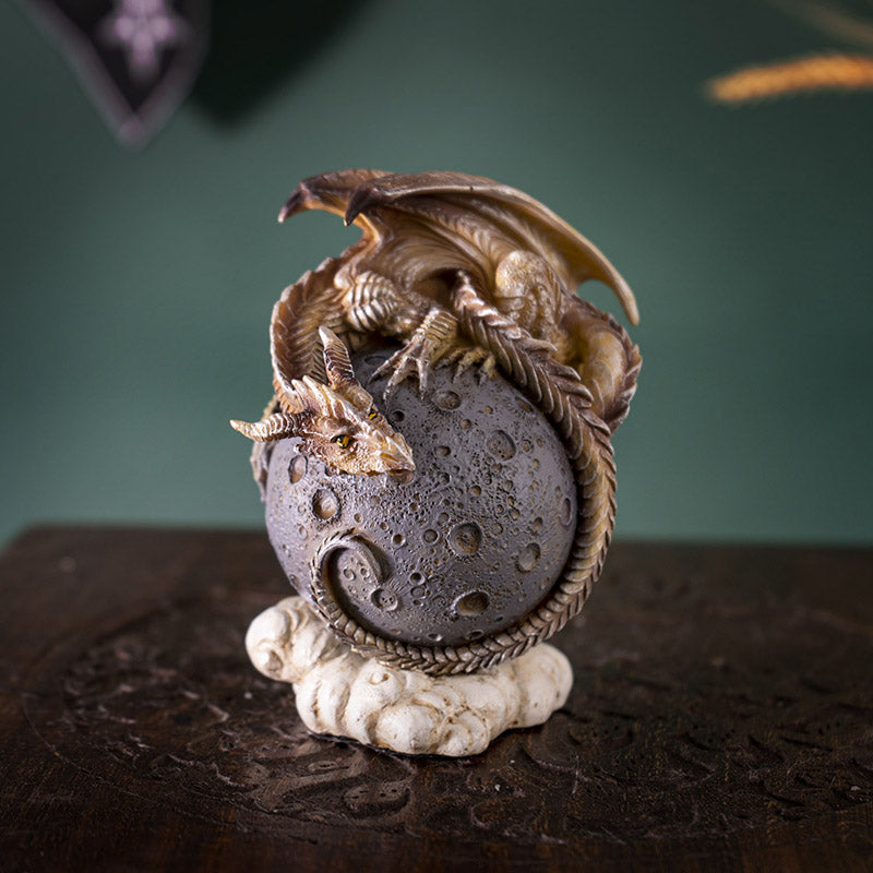 Figurine of a tan dragon on a gray moon orb