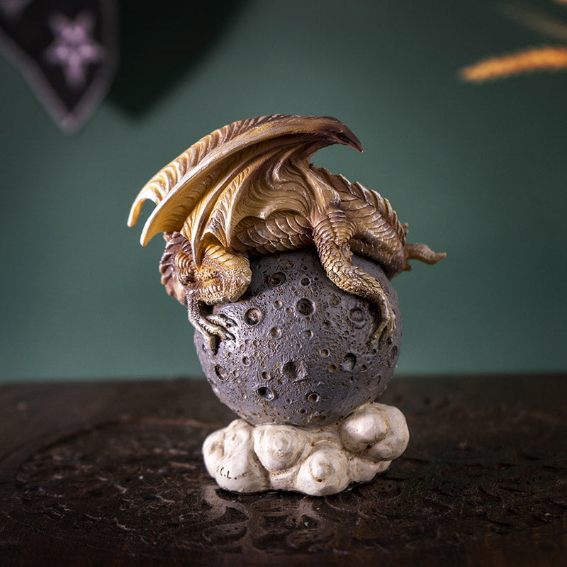 Figurine of a tan dragon on a gray moon orb, shown from the back