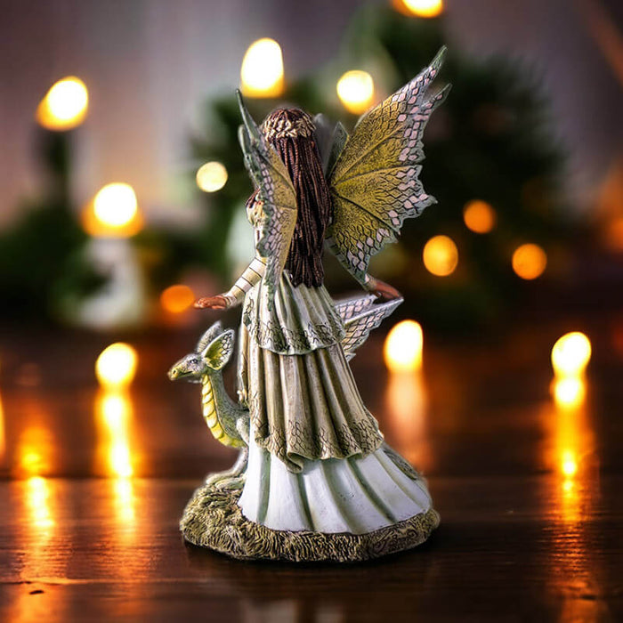 Figurine of a fairy dressed in green with matching wings and dragon. She has tanned skin and braided brown hair.