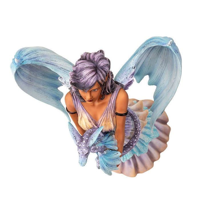 Figurine of a fairy with pale blue dragon wings and purple hair holding a dragon. Shown top down from above