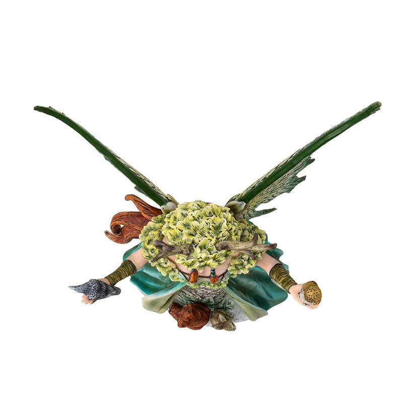 Figurine of a redhaired fairy in a green nature themed dress with birds in her hands and a fox and rabbit. Top-down view