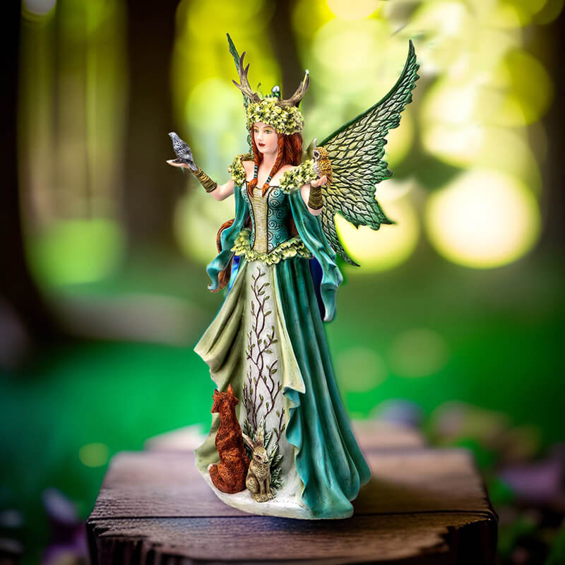 Figurine of a redhaired fairy in a green nature themed dress with birds in her hands and a fox and rabbit.