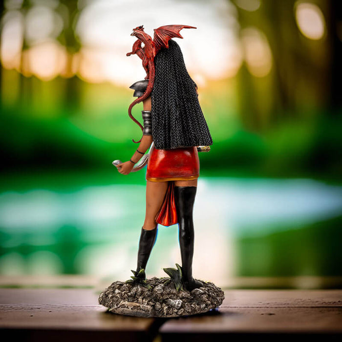 Figurine of a tanned skin woman with dark braided hair wearing black and red, holding a weapon with a ruby dragon on her shoulder
