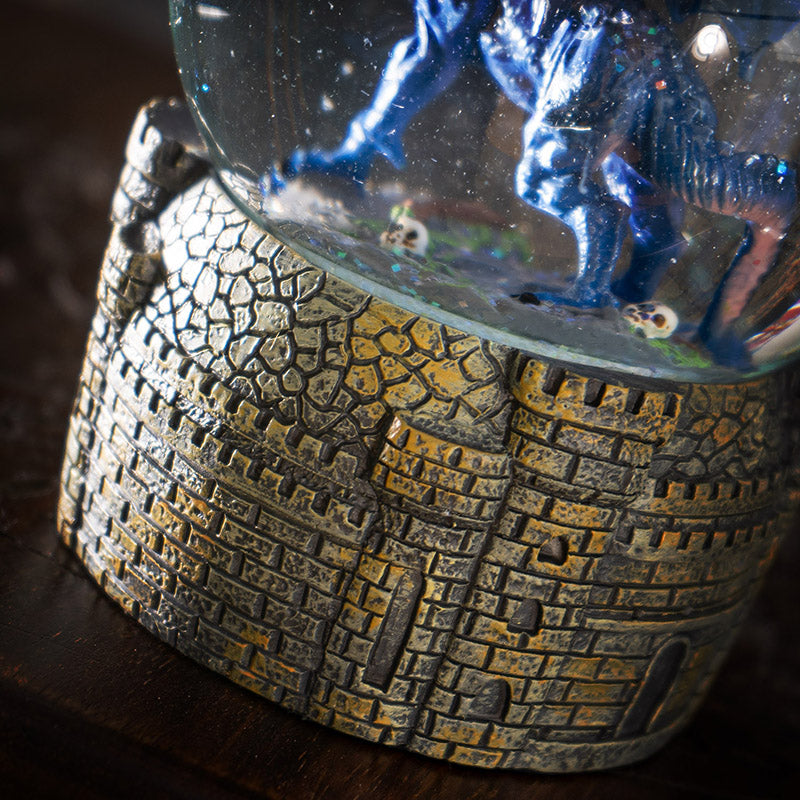 Snowglobe with blue dragon with red eyes within, castle base closeup