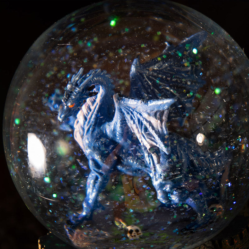 Snowglobe with blue dragon with red eyes within, glitter in the water