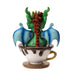 Figurine of a green dragon with blue wings and gold and red accents in a mug of chai. Back view