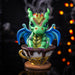 Figurine of a green dragon with blue wings and gold and red accents in a mug of chai.