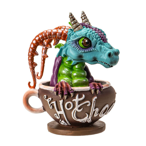 Figurine of a blue, green and purple dragon with red horns popping out from a faux mug of hot chocolate with white writing on brown.