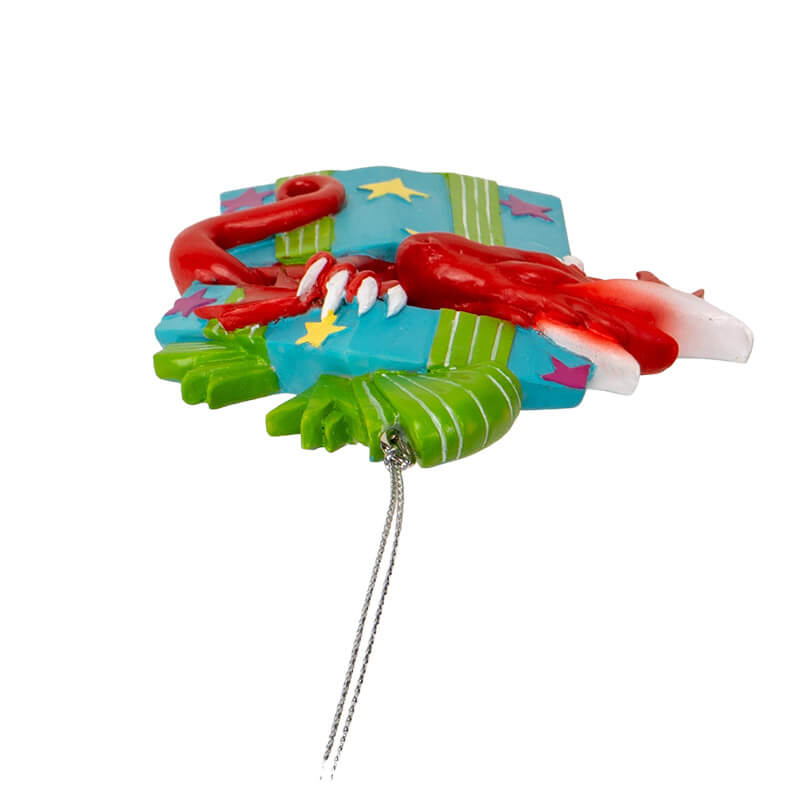 Ornament of red dragon popping out of a blue gift box with yellow and purple stars and green ribbon