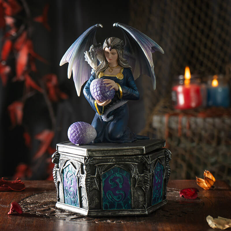 Trinket box with woman holding dragon egg on the lid, a dragon with purple-blue scales wrapped around her. Base of the box has purple and violet dragon designs.