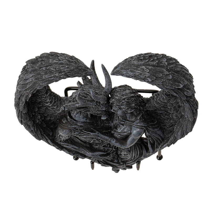 Figurine on stand of demon and angel forming a heart with their wings, done in faux-stone. Shown top-down