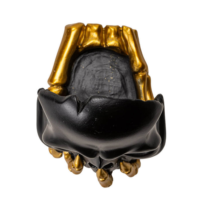 Black skull with golden boney hand candleholder, shown top down