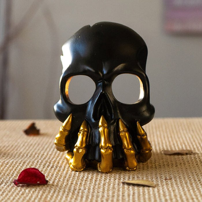 Black skull with golden boney hand candleholder