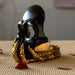 Black skull with golden boney hand candleholder, shown from the side with candle