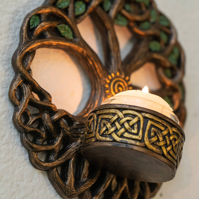 Tree of Life candleholder wall plaque with Celtic knot designs and spiral, shown with glowing candle