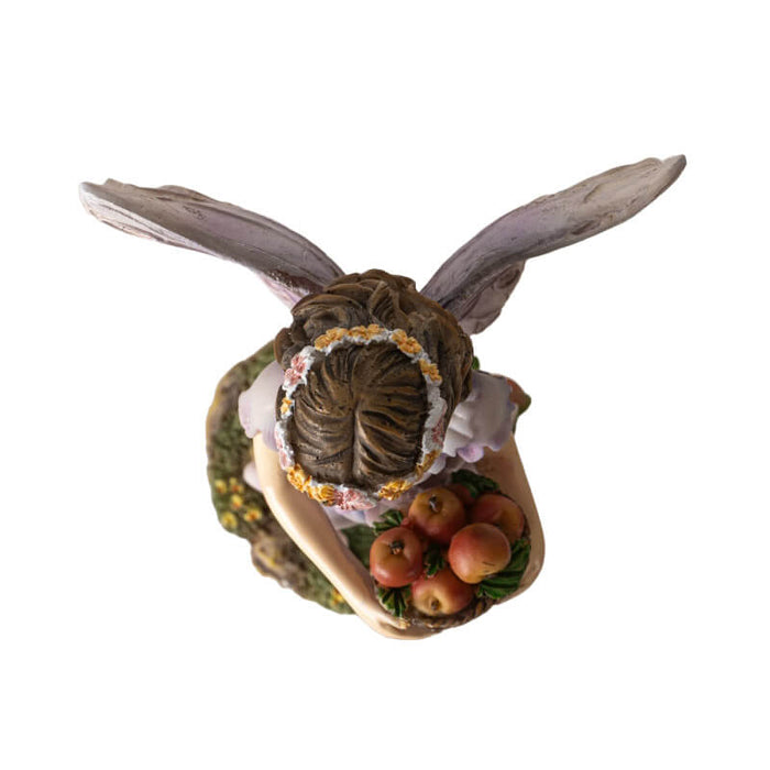 Figurine of a fairy with brown hair and flower crown carrying a basket of apples. Top down view