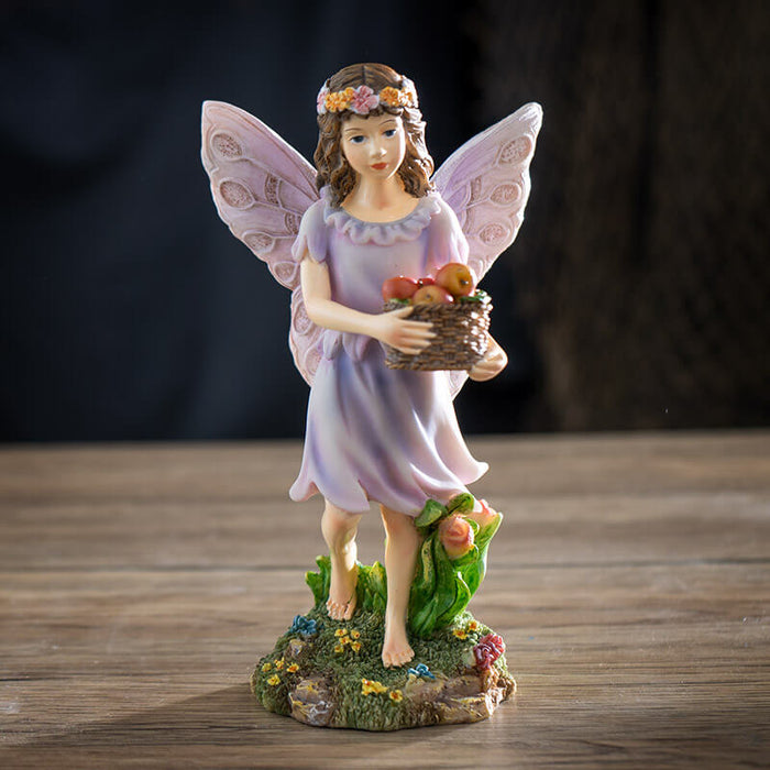 Figurine of a fairy with brown hair and flower crown carrying a basket of apples.
