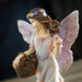 Fairy figurine of pixie with basket full of fruit, holding one. Brown hair, flower corn, pale pink dress & wings