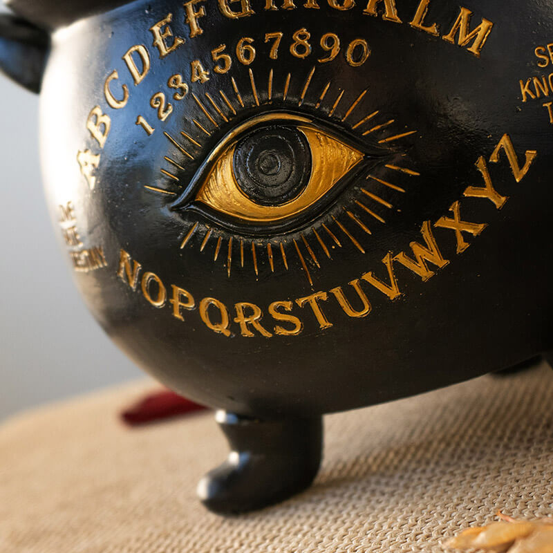 Closeup of gold Ouija designs and eye on black