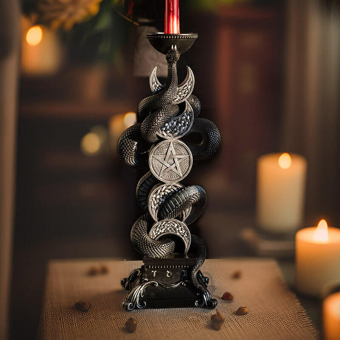 Candleholder of black snake twining through moon phases in silver with spot for taper candle at the top.