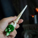 Magic wand with faux-wood staff, face and braid, topped with green crystal cluster