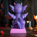 Figurine of a dragon sitting on a pink base that says "I LOVE DRAGONS!" The dragon is purple and pink with red heart glasses and a little burst of fire., shown from the back